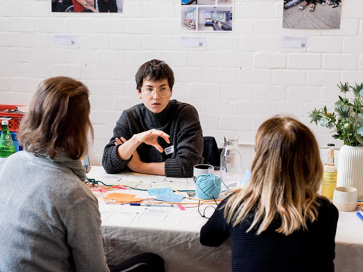 Arbeitssituation während des Workshops "Verwaltung und Soziale Innovation". Drei Personen befinden sich in einem Gespräch.
